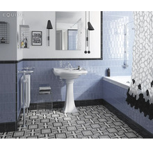 Badkamer met blauw betegelde wand, wastafel, bad en een vloer met motief.