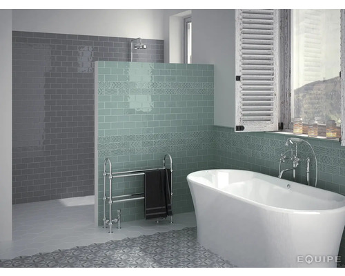 Badkamer met bad, betegelde wand en handdoekradiator