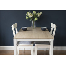 Eettafel met houten tafelblad, witte stoelen en decoratieve schalen