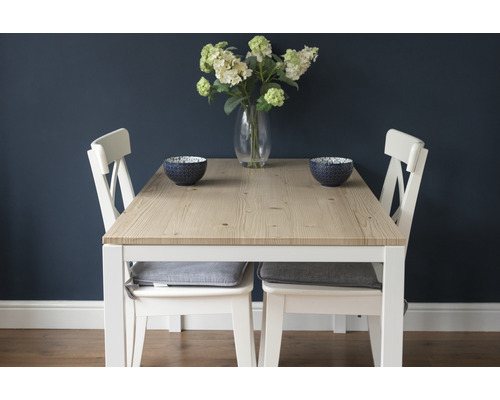 Eettafel met houten tafelblad, witte stoelen en decoratieve schalen