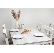 Eettafel met stoelen, borden, brood, pepermolen en decoratie