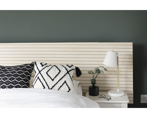 Slaapkamer met bed, kussens met patroon en nachtkastlamp