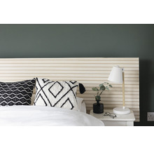 Slaapkamer scène met bed, nachtkastje, lamp en decoratieve kussens.