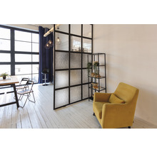 Woonkamer met eettafel, stoelen, scheidingswand, rek en fauteuil.