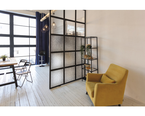 Woonkamer met eettafel, stoelen, scheidingswand, rek en fauteuil.