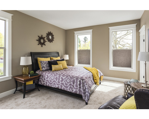 Slaapkamer met bed, nachtkastjes en ramen met rolgordijnen van textiel