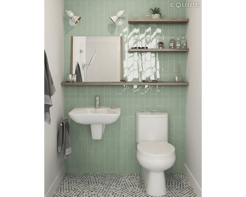 Badkamer met toilet, wastafel, spiegel, planken en groene tegels.