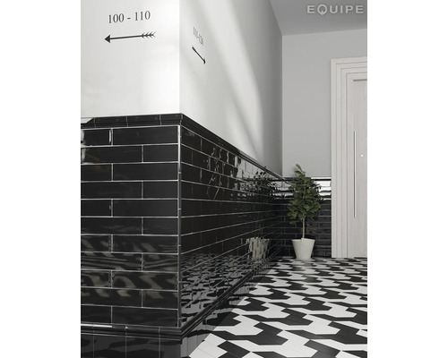 Hal met zwart betegelde wanden en een zwart-wit gemusterde vloer.