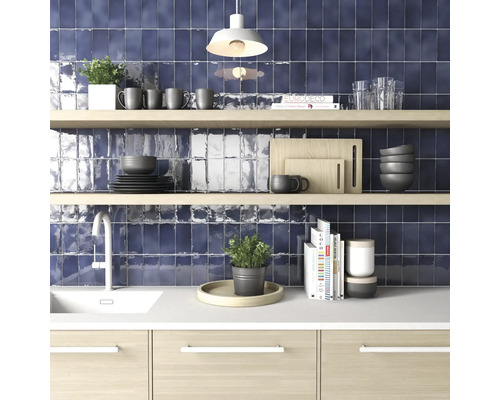 Keukenscène met spoelbak, kraan, aanrecht, planken en donkerblauwe tegels