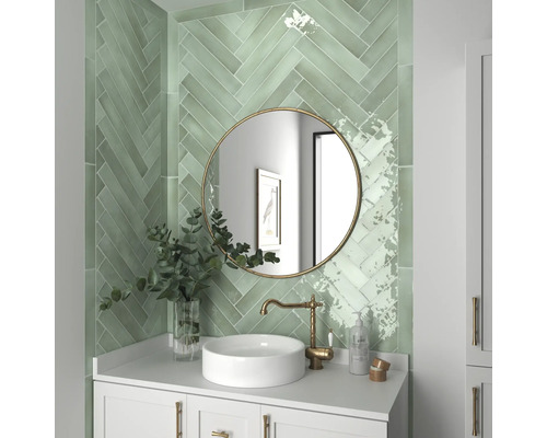 Badkamer met groene wandtegels in visgraatmotief, ronde spiegel en wastafel