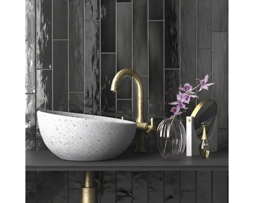 Badkamer wastafel met kraan, spiegel en decoratie op donker oppervlak voor donkere tegels