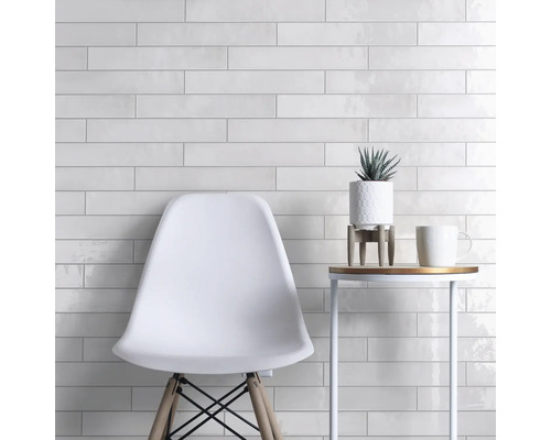 Wanddecoratie met witte, langwerpige tegels, gecombineerd met een stoel en een bijzettafel.