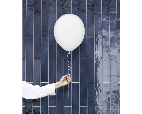 Hand houdt witte ballon vast voor blauwe wandtegel