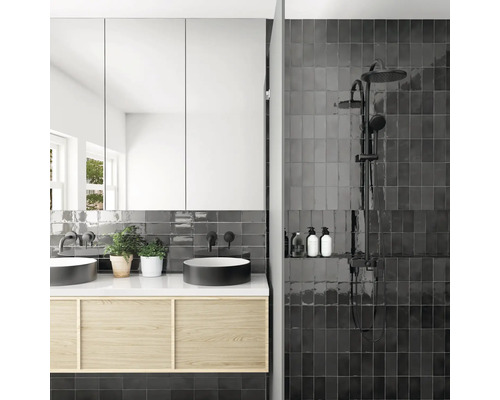 Lichte badkamer met dubbele wastafel, spiegelkast en douche met donkere tegels.