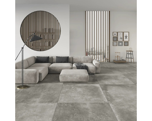 Woonkamer met grijze vloertegels, hoekbank, staande lamp en wanddecoraties voor een lichte en georganiseerde sfeer.