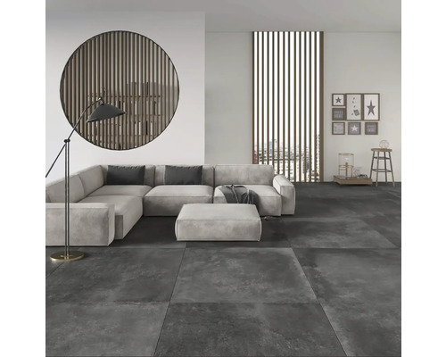 Moderne woonkamer met grootformaat vloertegels in steenlook, hoekbank en decoratieve houten elementen.