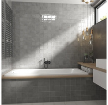 Moderne badkamer met grijze tegels, ligbad en wastafel