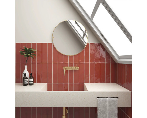 Moderne badkamer met rode tegels, ronde spiegel en opzetwastafel.