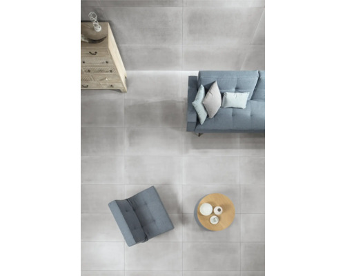 Woonkamer met grijze vloertegels, bank, fauteuil en commode