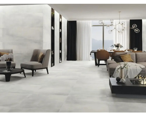 Lichte woonkamer met tegelvloer, fauteuils, bank, eettafel en boekenkasten