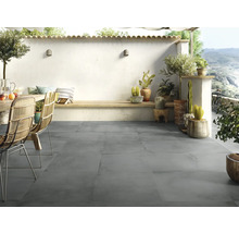 Terras met grijze vloertegels, tuinmeubelen en decoratieve planten