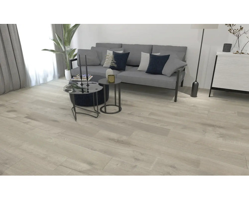 Lichte woonkamer met bank, tafel en houten vloer.