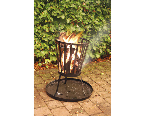 Metalen vuurkorf met houtblokken en vlammen in de tuin