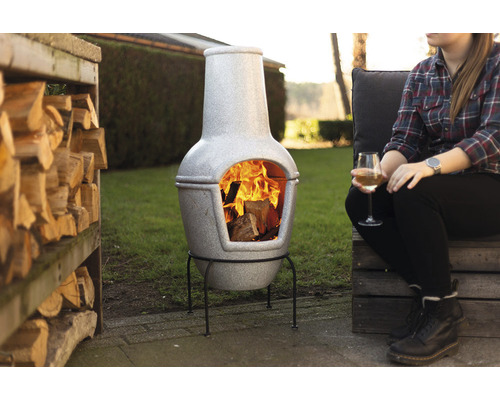 Grijze terracotta chiminea oven met brandhout in de tuin
