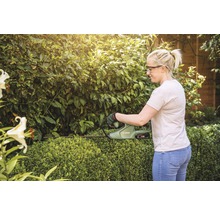 Vrouw snoeit heg met een accu heggenschaar