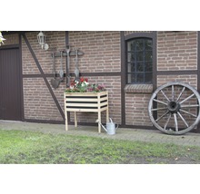Houten bloembak met bloemen, gieter en wagenwiel voor een bakstenen gebouw
