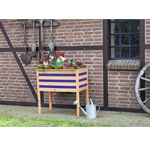 Houten bloembak met bloemen en gieter voor bakstenen muur