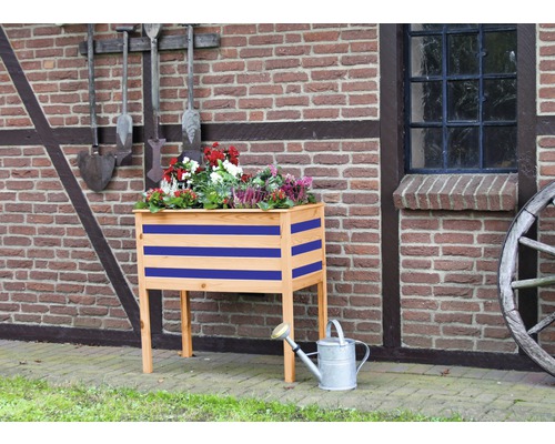 Houten bloembak met bloemen en gieter voor bakstenen muur