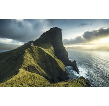 Landschap met een vuurtoren op een groene klif aan zee onder een bewolkte hemel.