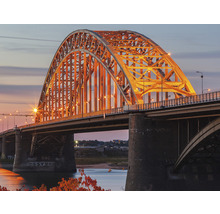 Gezicht op een verlichte boogbrug in de schemering.