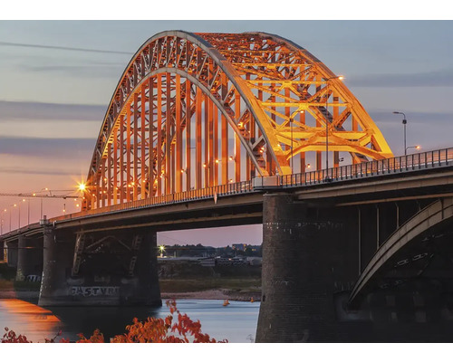 Gezicht op een verlichte boogbrug in de schemering.