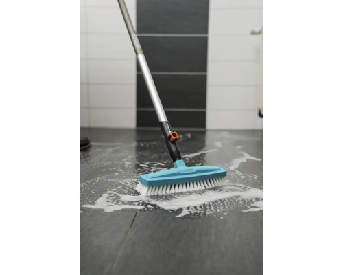 Borstel met steel reinigt tegelvloer