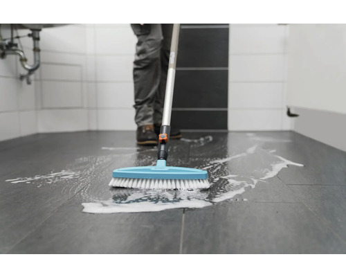 Persoon reinigt badkamervloer met schoonmaakborstel