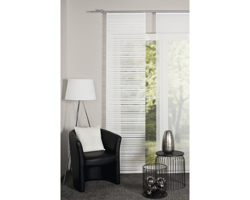 Woonkamer met schuifgordijnen, fauteuil, staande lamp en decoratieve objecten voor een gezellige sfeer.