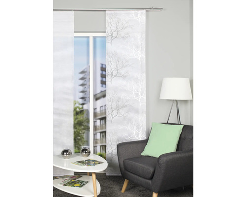 Woonkamer met schuifgordijnen met boommotief voor het raam, fauteuil en bijzettafel