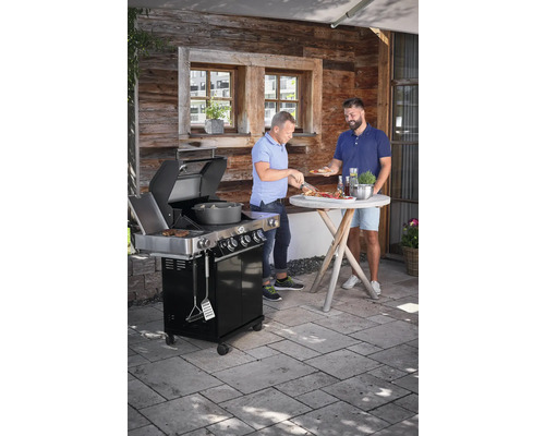 Twee mannen barbecueën op een zwarte gasbarbecue buiten op een terras.