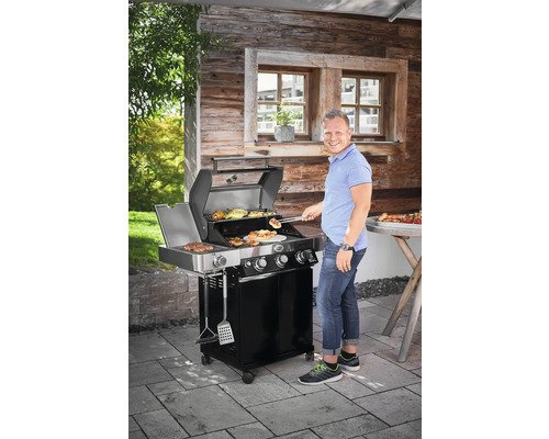 Man grilt eten op een gasbarbecue in de buitenlucht.