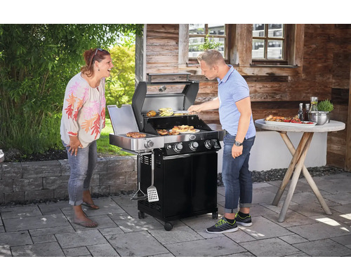Twee mensen bij de barbecue met bijzettafel op een terras