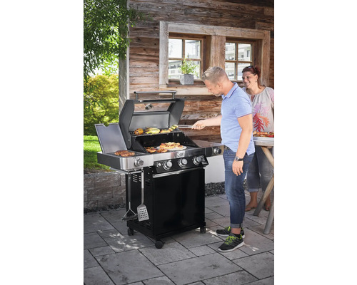 Mensen grillen op een zwarte gasbarbecue in de buitenlucht.