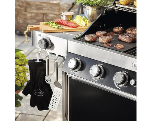 Roestvrijstalen barbecue met gegrild voedsel, barbecuetools en ingrediënten op een tuintafel