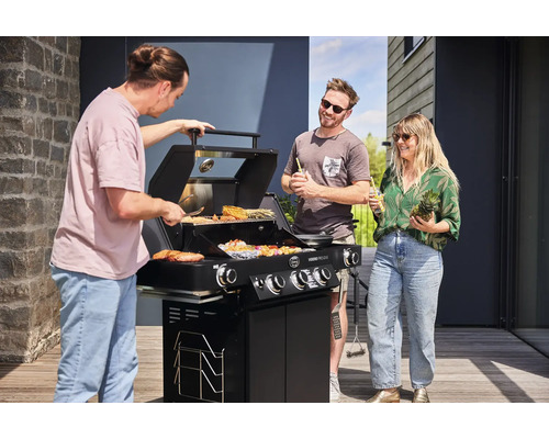 Mensen grillen met een gasbarbecue in de buitenlucht. Op de barbecue liggen vlees, groenten en spiesen.