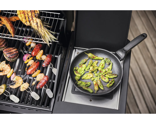 Barbecue met bereide gerechten zoals groenten, vlees en paprika''s in een koekenpan