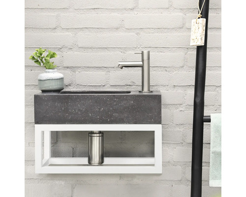 Wastafel met kraan, plant en handdoekenrek voor een bakstenen muur