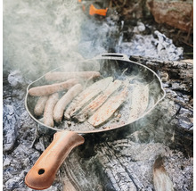 Braadworst en courgette in een gietijzeren pan boven een kampvuur