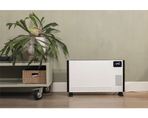 Witte convectorkachel naast een bijzettafel met een kamerplant en een mand