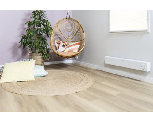 Woonkamer met rotan stoel, rond jute tapijt, kamerplant en wandverwarming